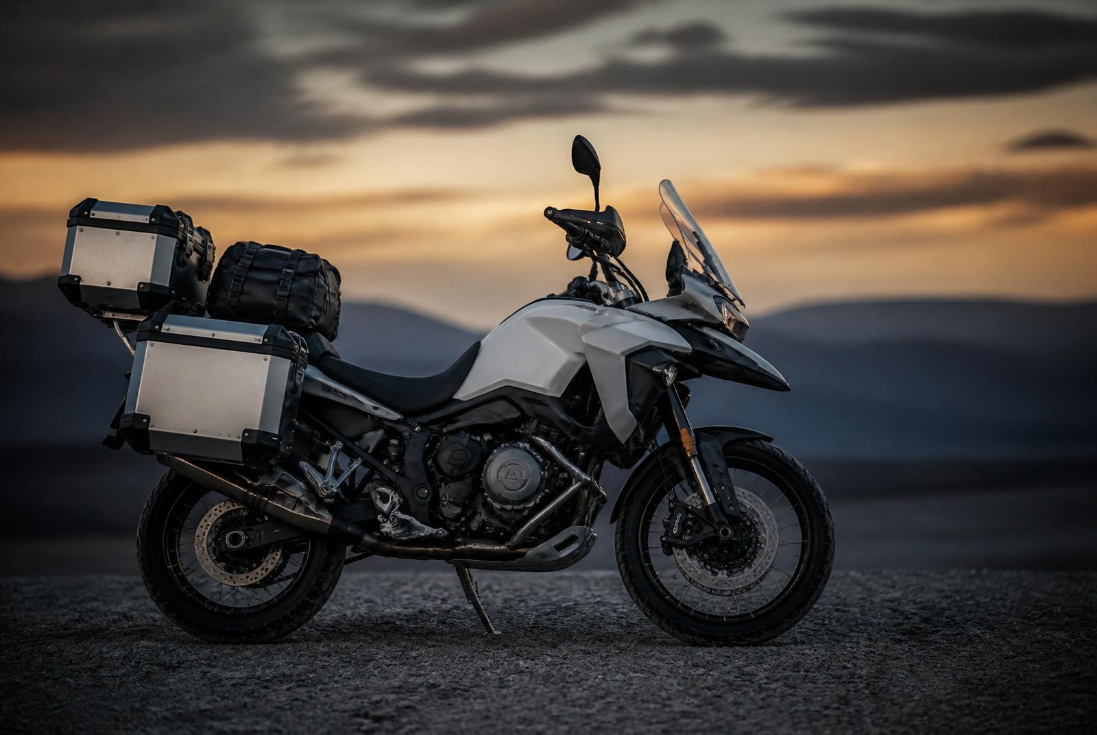 A loaded adventure motorcycle parked against an empty landscape at dusk